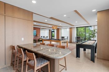 Game Lounge with billiards, shuffleboard, wet bar, and multi-sport golf simulator at Lilia Apartments in Lilydale, MN 55118